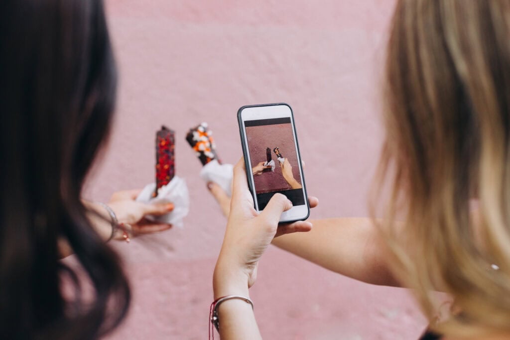two people taking a picture of a dessert