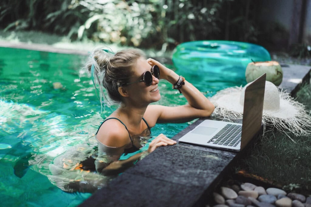 person working on laptop while in pool