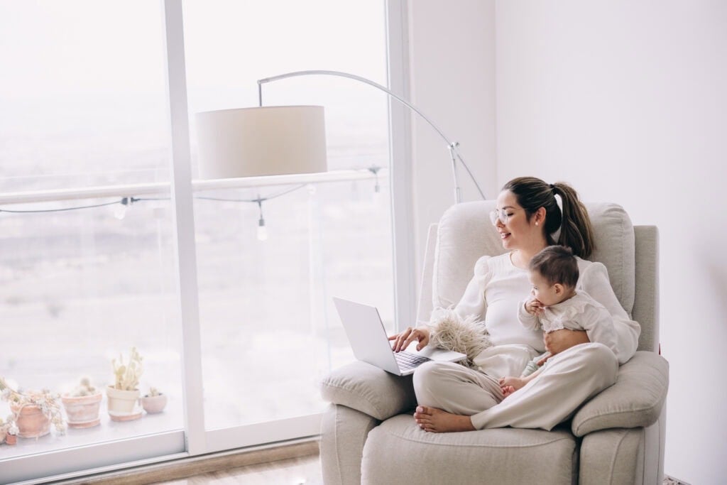 mom working on laptop while holding baby 