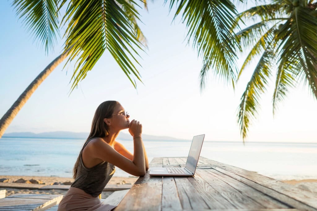 person working on laptop on the beach